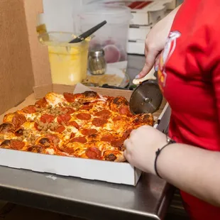 a woman cutting a pepperoni pizza