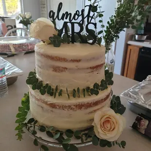 a wedding cake with roses and greenery