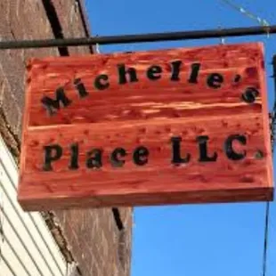 a wooden sign hanging from the side of a building