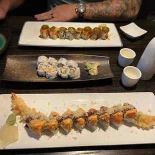 a man sitting at a table with plates of sushi