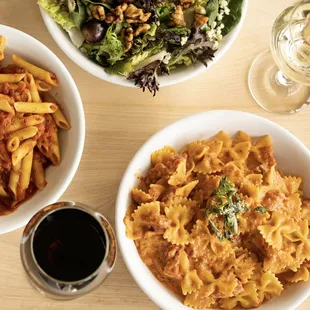 two bowls of pasta and a glass of wine