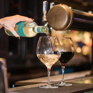 a person pouring a glass of wine