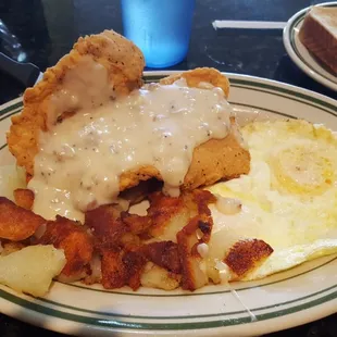 Country fried chicken with gravy, eggs over easy, and American fries.
