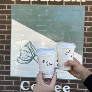 hand holding two cups of coffee