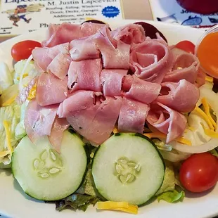 a salad with ham, lettuce, tomatoes, cucumbers, and hard boiled eggs