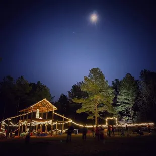 a full moon over a barn with string lights