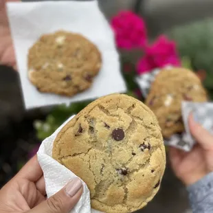 two hands holding a chocolate chip cookie