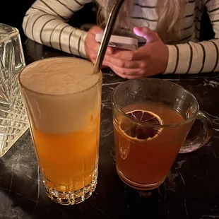 a woman sitting at a table with a drink and a cell phone