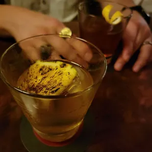 a person holding a lemon slice in a glass
