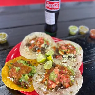 three tacos on a red plate with a bottle of coke