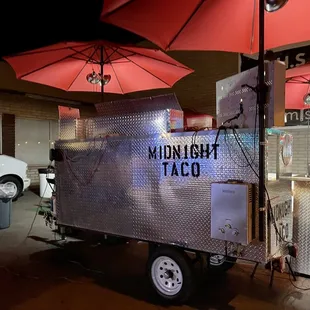a food cart with red umbrellas