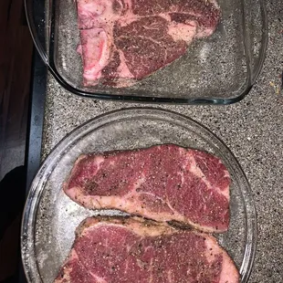 two steaks in glass dishes