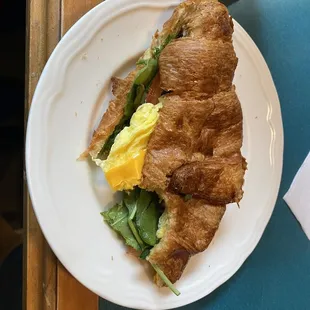 Veggie breakfast sandwich with tomato, avocado, spinach, and eggs.