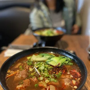 a woman sitting at a table with a bowl of soup