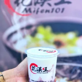 a hand holding a cup of yogurt