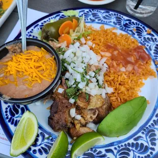 Carnitas dinner plate with rice, beans and tortillas.