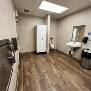Restroom is spacious and has a toilet, urinal and baby changing table