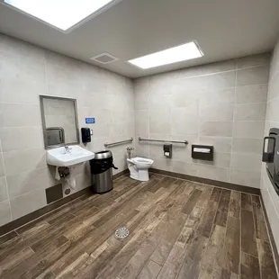 Restroom is spacious and has a toilet, urinal and baby changing table