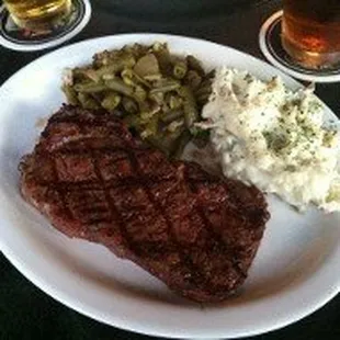a plate of steak, mashed potatoes, and green beans
