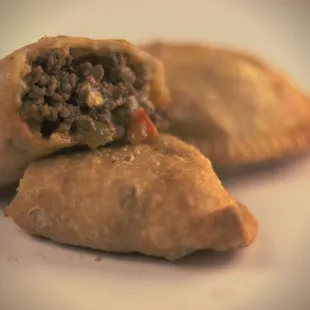 a close up of a meat and cheese empanada