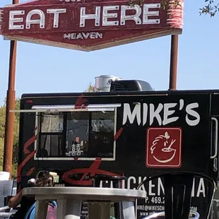 a man sitting at a table in front of a food truck