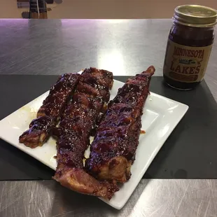 a plate of ribs and a jar of bbq sauce