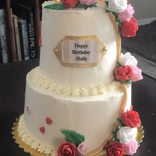 Mini two tier celebration cake with hand shaped fondant flowers, leaves and vines