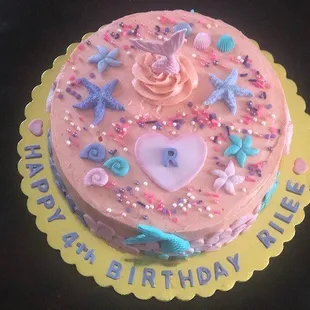 A little girl, pretty in pink mermaid birthday cake