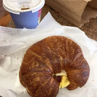 Bacon egg and cheese on a croissant and small coffee