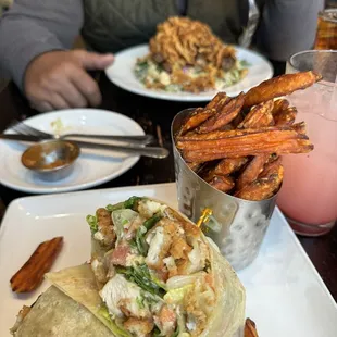 Foreground: Caesar chicken wrap with sweet potato fries, really, really good. Background steak salad with fried onions on top.