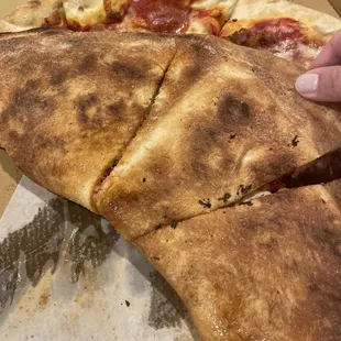 a hand grabbing a piece of pizza