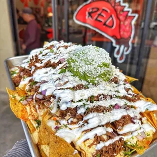 Loaded Nachos w/ beef birria, queso, beans, cilantro, onions, topped off w/ sour cream and guacamole