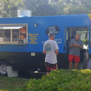 two men standing in front of a food truck
