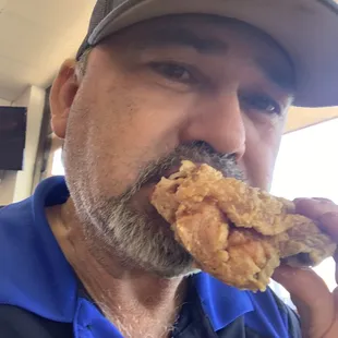 a man eating a piece of fried chicken