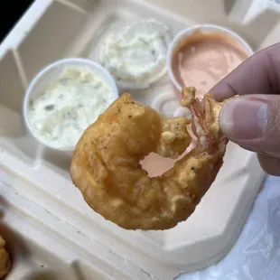 a hand holding a fried shrimp