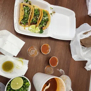 a table with tacos, sauces, and condiments
