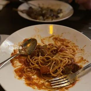 End of bowl of Pasta Napoletana, homemade meatballs in there YUM. Rack of lamb with fettuccini dish in the background.