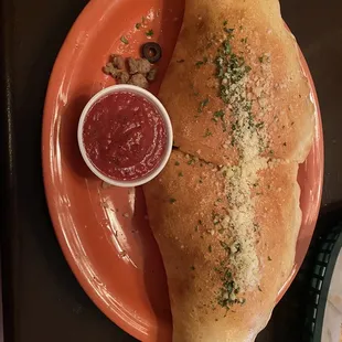 a calzone with a side of sauce
