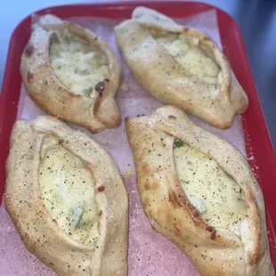 four baked pizzas on a red tray