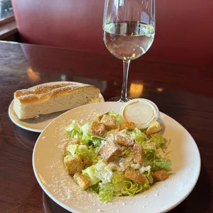 side Caesar salad, garlic bread, glass of Sauvignon Blanc