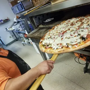 a man taking a pizza out of the oven
