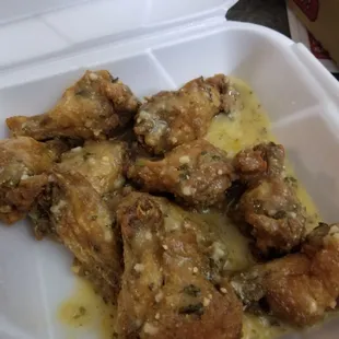 chicken wings in sauce in a styrofoam container