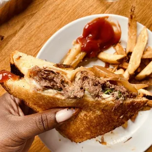 a person holding a sandwich and french fries