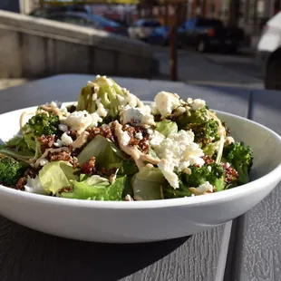 a bowl of broccoli, cauliflower, and feta cheese