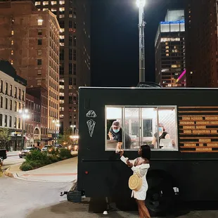 a woman standing in front of a food truck