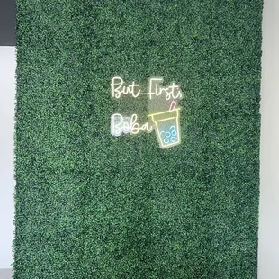 a boxwood wall with a neon sign