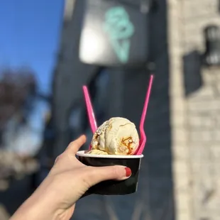 a hand holding a cup of ice cream