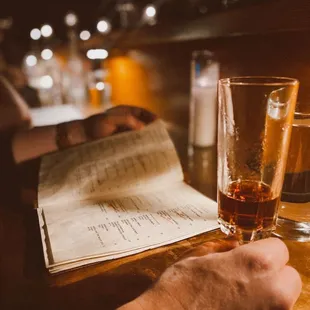 a person reading a menu and a glass of beer