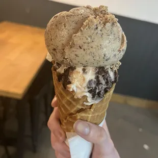 2 half-scoops of City That Never Sleeps (top) and Sundae Fundae (bottom) on a waffle cone.