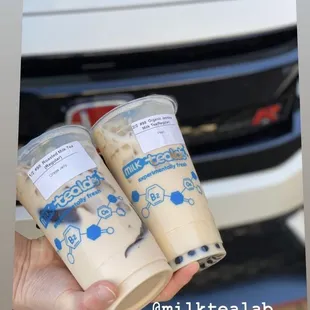 a hand holding two cups of milk tea
